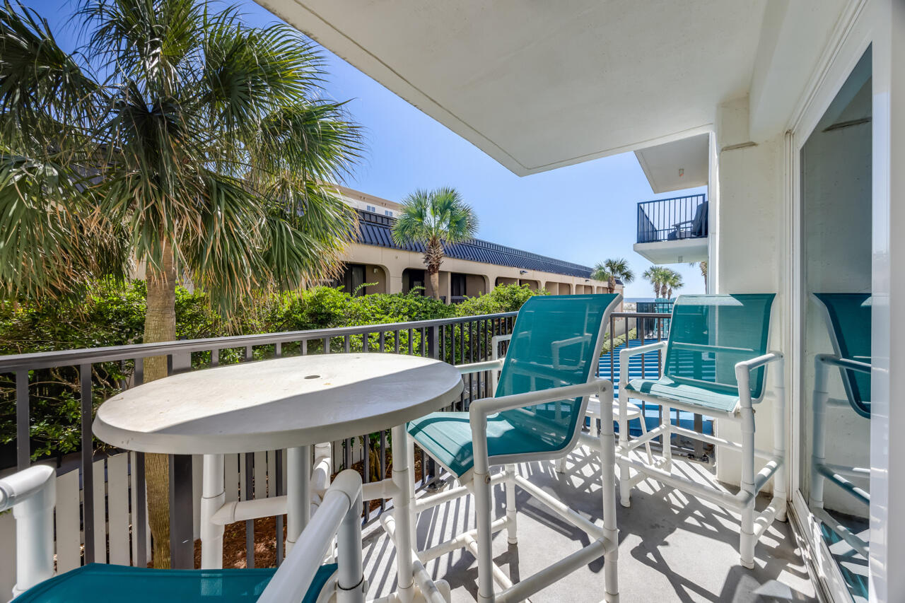 1114 Santa Rosa Boulevard, Unit 208 Fort Walton Beach, FL 32548 - Photo 27 of 73 a view of a patio with table and chairs potted plants and palm tree