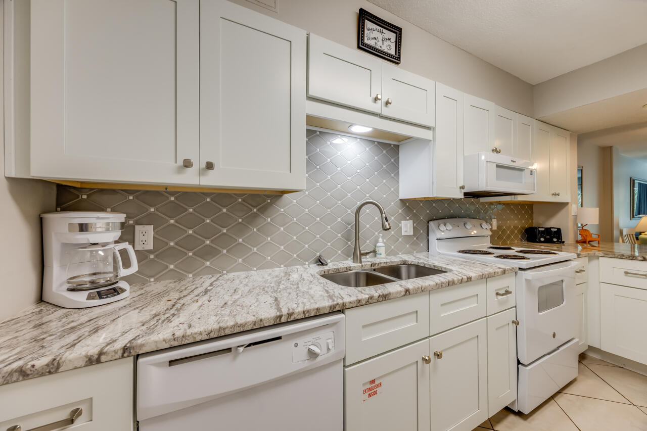 1114 Santa Rosa Boulevard, Unit 208 Fort Walton Beach, FL 32548 - Photo 6 of 73 a kitchen with granite countertop white cabinets and white appliances