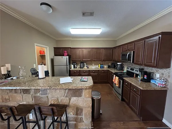 a kitchen with granite countertop a table chairs microwave and cabinets