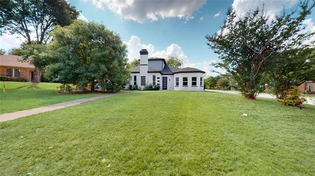 a view of a house with a big yard and large trees