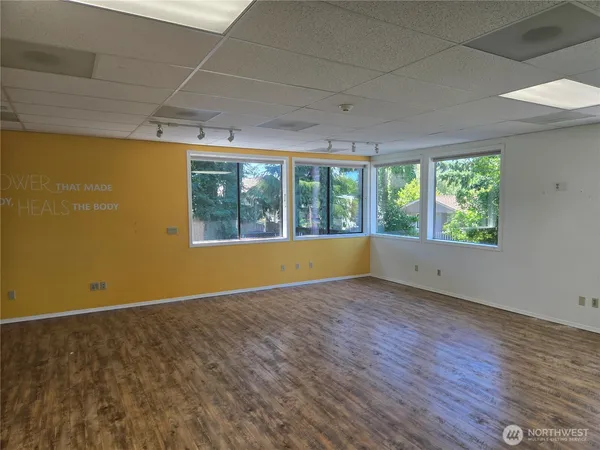 an empty room with wooden floor and windows