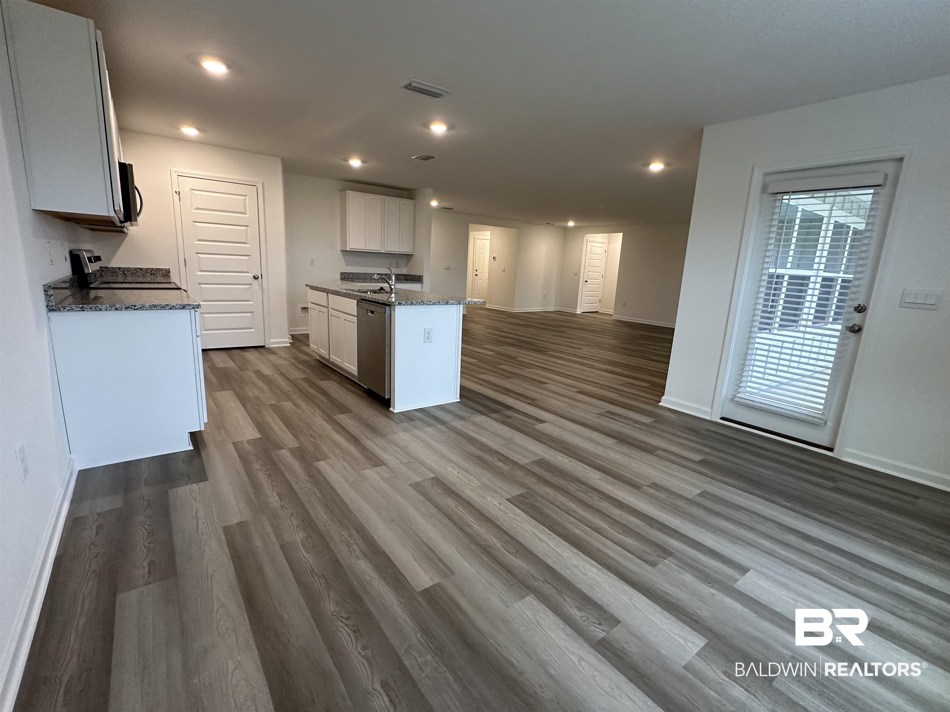 22275 Aleutian Avenue Foley, AL 36535 - Photo 8 of 72 Kitchen with stainless steel appliances, dark stone countertops, an island with sink, white cabinets, and dark hardwood / wood-style flooring