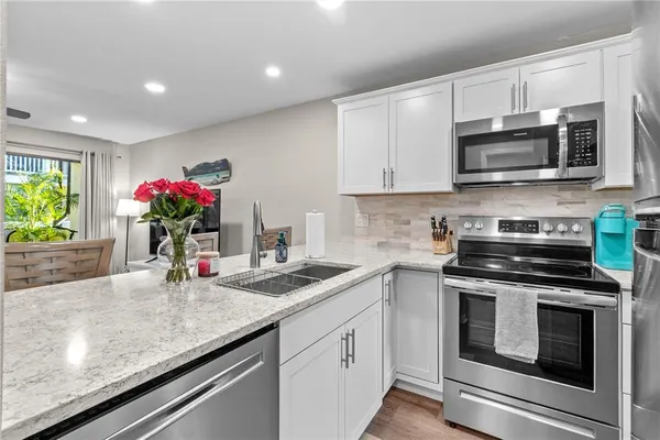 a kitchen with granite countertop a sink stainless steel appliances and cabinets