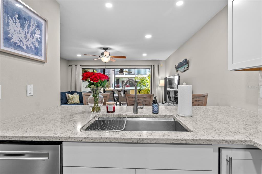1752 Stickney Point Road, Unit 102 Sarasota, FL 34231 - Photo 15 of 50 a kitchen with kitchen island granite countertop a sink and a white cabinets with potted plants