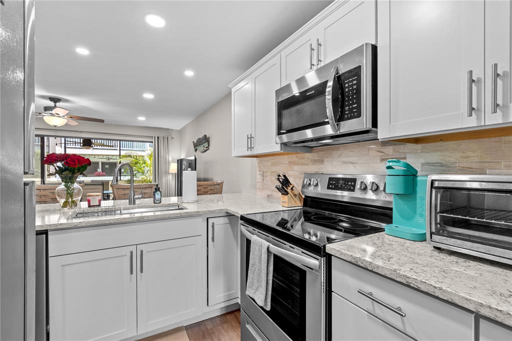 1752 Stickney Point Road, Unit 102 Sarasota, FL 34231 - Photo 17 of 50 a kitchen with stainless steel appliances granite countertop a sink and a stove