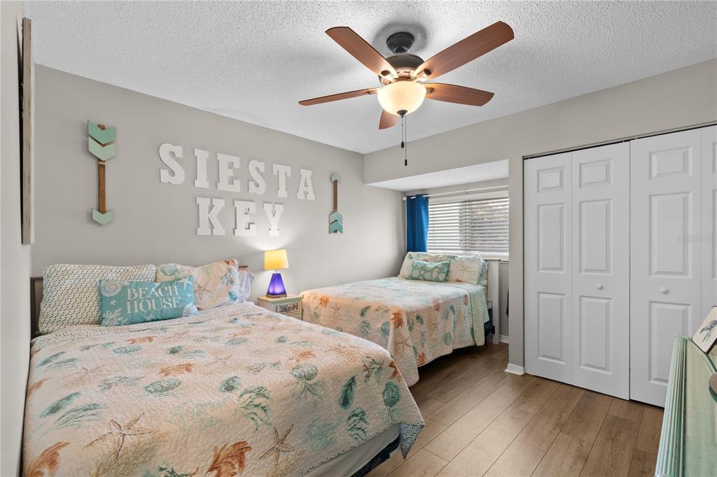 1752 Stickney Point Road, Unit 102 Sarasota, FL 34231 - Photo 29 of 50 a bedroom with two separate beds and a chandelier