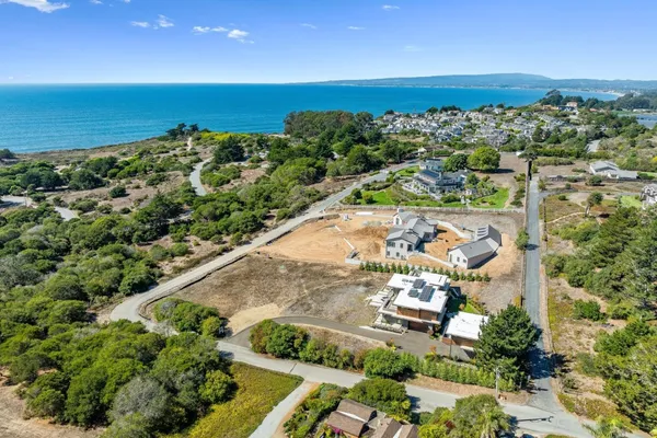an aerial view of ocean and residential houses with outdoor space