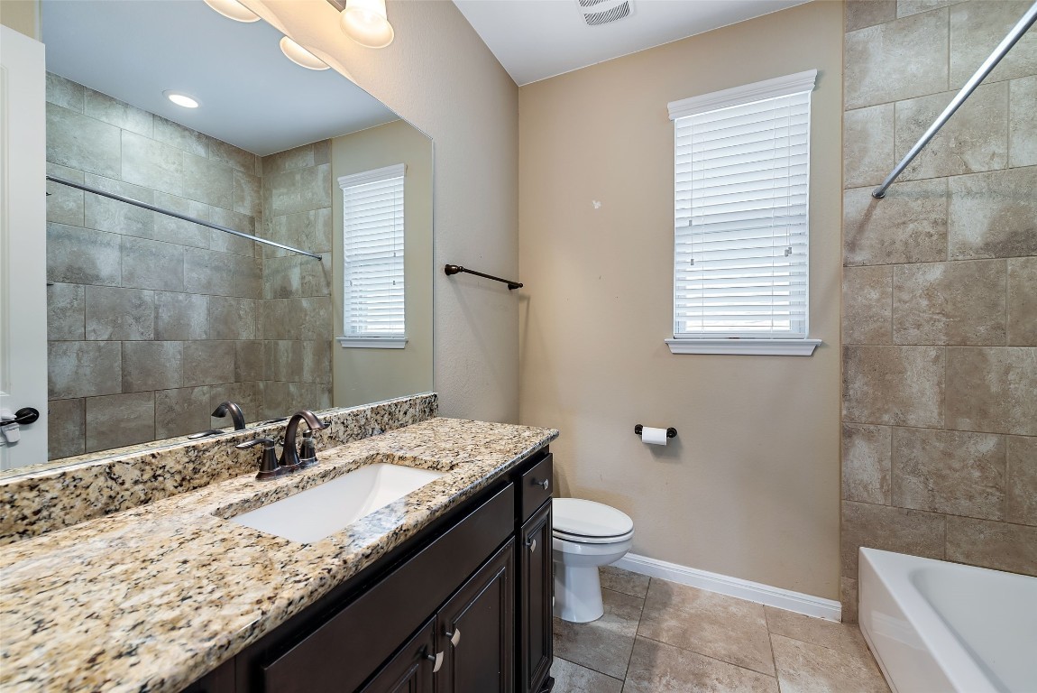 2000 Manada Trail Leander, TX 78641 - Photo 31 of 36 A well-appointed bathroom features a spacious granite vanity and tiled shower surround.