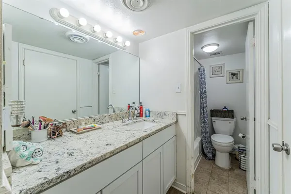 a bathroom with a granite countertop sink a toilet and a mirror
