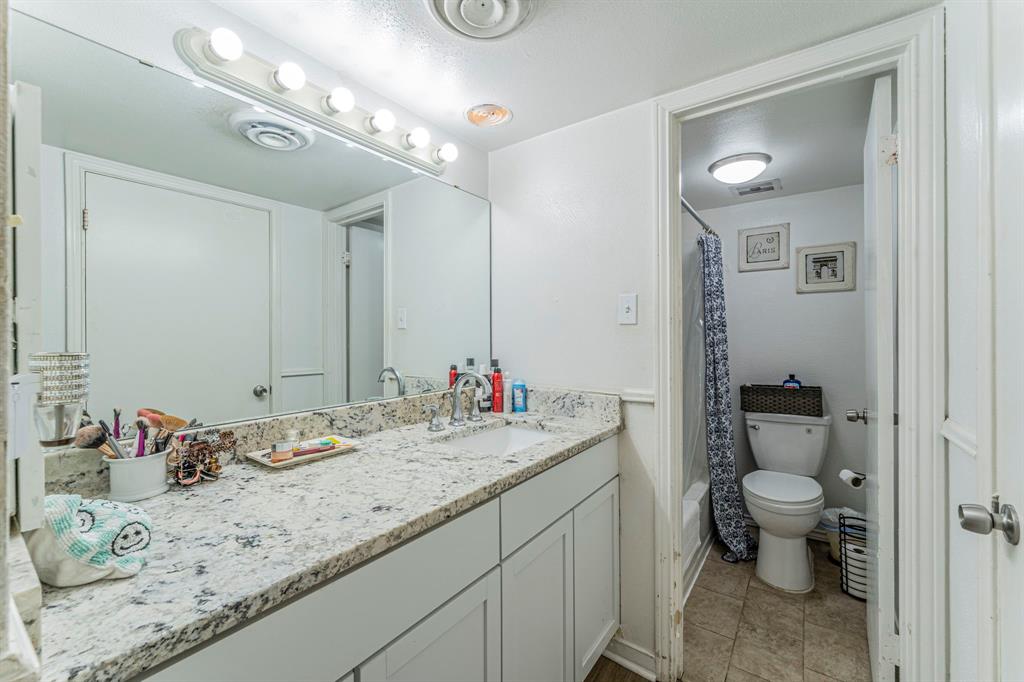558 E Avenue, Unit B Grand Prairie, TX 75050 - Photo 8 of 16 a bathroom with a granite countertop sink a toilet and a mirror