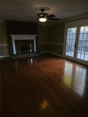 a view of wooden floor fire place and windows in an empty room
