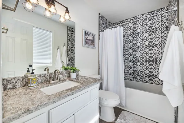a bathroom with a granite countertop sink a toilet and shower
