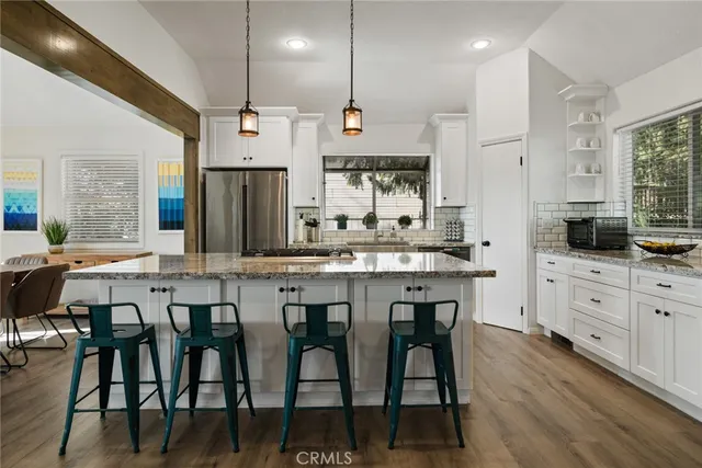 an open kitchen with granite countertop a sink and white cabinets