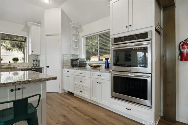 a kitchen with stainless steel appliances white cabinets and a stove a oven with wooden floor