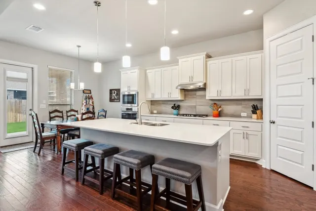a kitchen with white cabinets and chairs