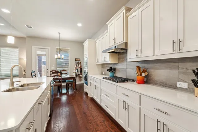 a kitchen with white cabinets sink and stove