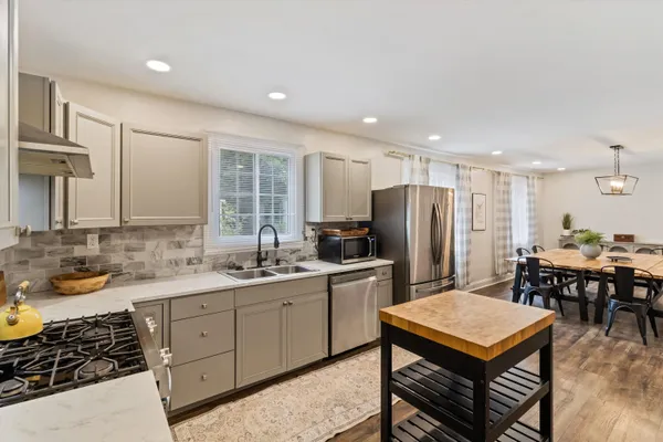 a kitchen with a sink a stove a refrigerator and chairs
