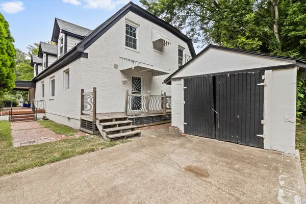 a view of a white house with a large space area and wooden fence