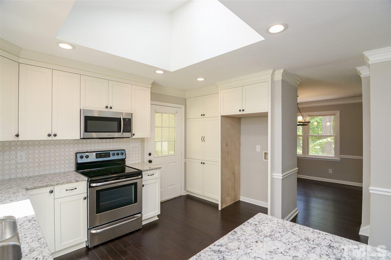 131 Lin Tilley Road Durham, NC 27712 - Photo 13 of 25 a kitchen with stainless steel appliances kitchen island granite countertop a stove a sink and a refrigerator