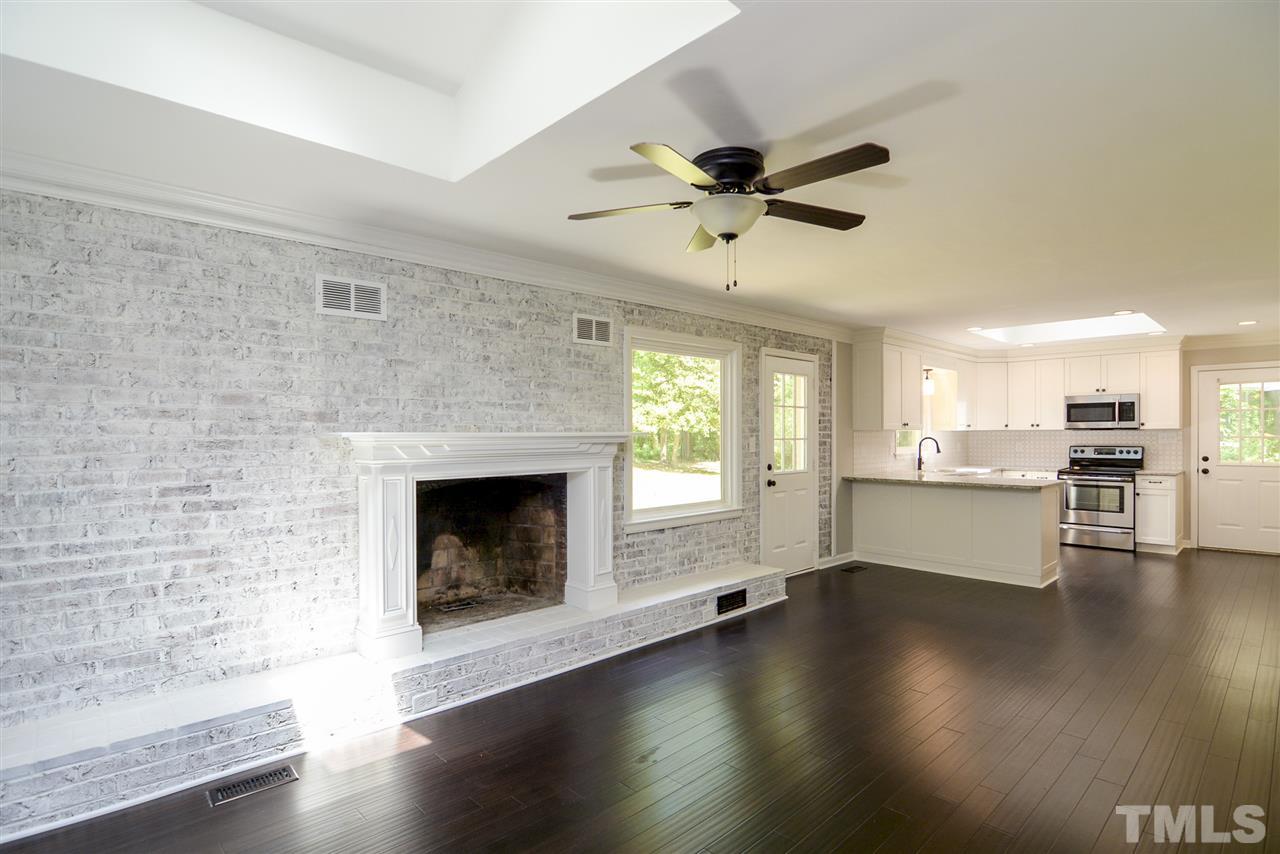 131 Lin Tilley Road Durham, NC 27712 - Photo 10 of 25 an empty room with wooden floor fireplace and windows