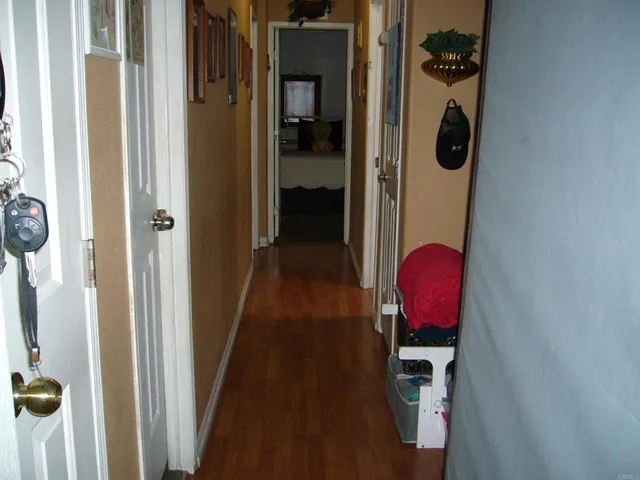 a view of a hallway with wooden floor and a utility room
