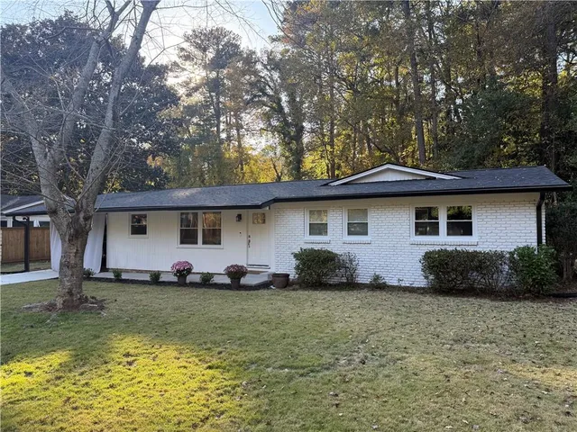 a front view of a house with a garden and trees