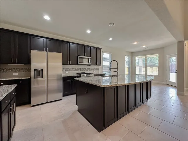 a large kitchen with kitchen island granite countertop wooden cabinets a sink and dishwasher