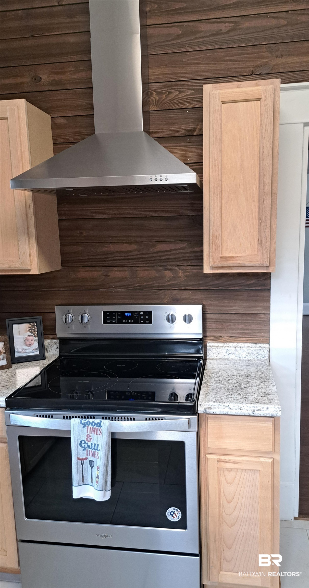 110 South Main Street Evergreen, AL 36401 - Photo 10 of 27 Stainless steel range with a coordinating hood, set against a horizontal wood-paneled accent wall