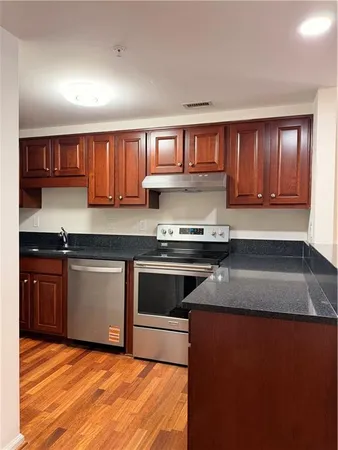 a kitchen with granite countertop a stove top oven sink and cabinets