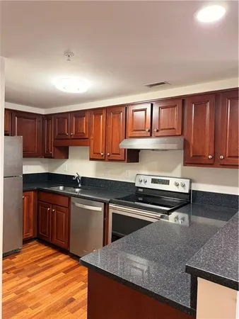 a kitchen with stainless steel appliances granite countertop a stove a sink dishwasher and a microwave oven with wooden cabinets