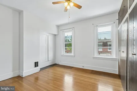 an empty room with wooden floor closet and windows
