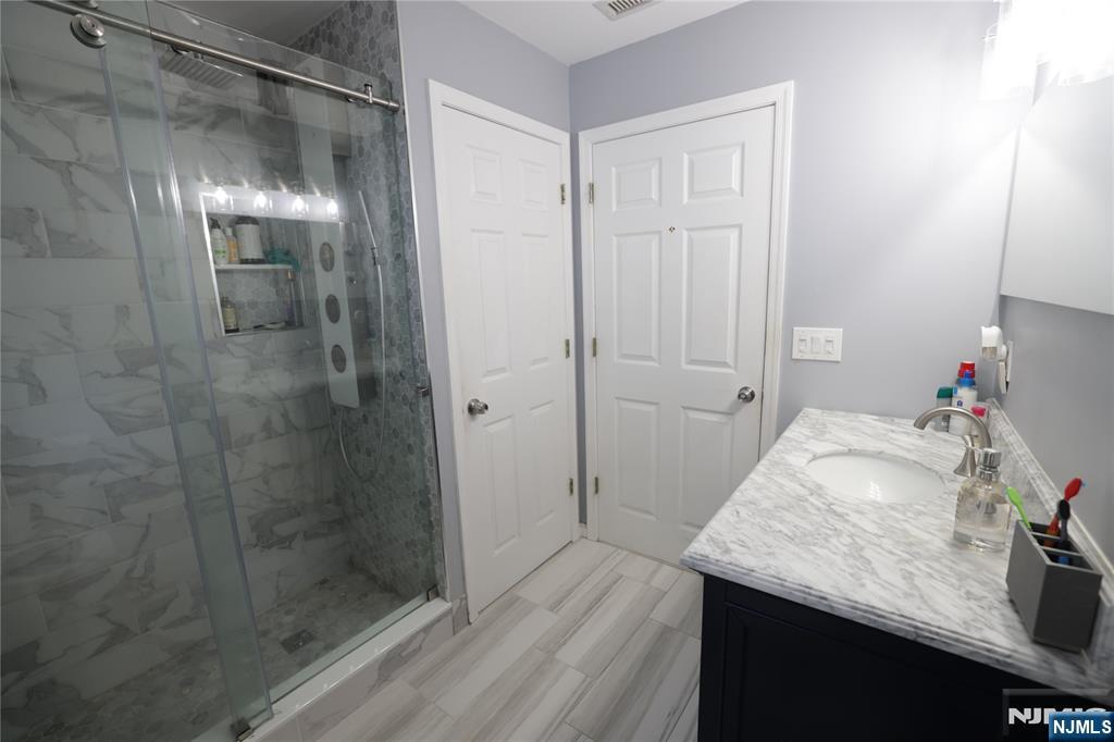 59 Spring Valley Avenue Hackensack, NJ 07601 - Photo 9 of 26 a bathroom with a granite countertop sink a shower and a mirror