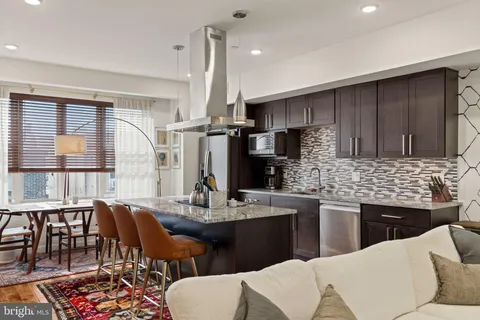 a kitchen with stainless steel appliances kitchen island granite countertop a table chairs and a refrigerator