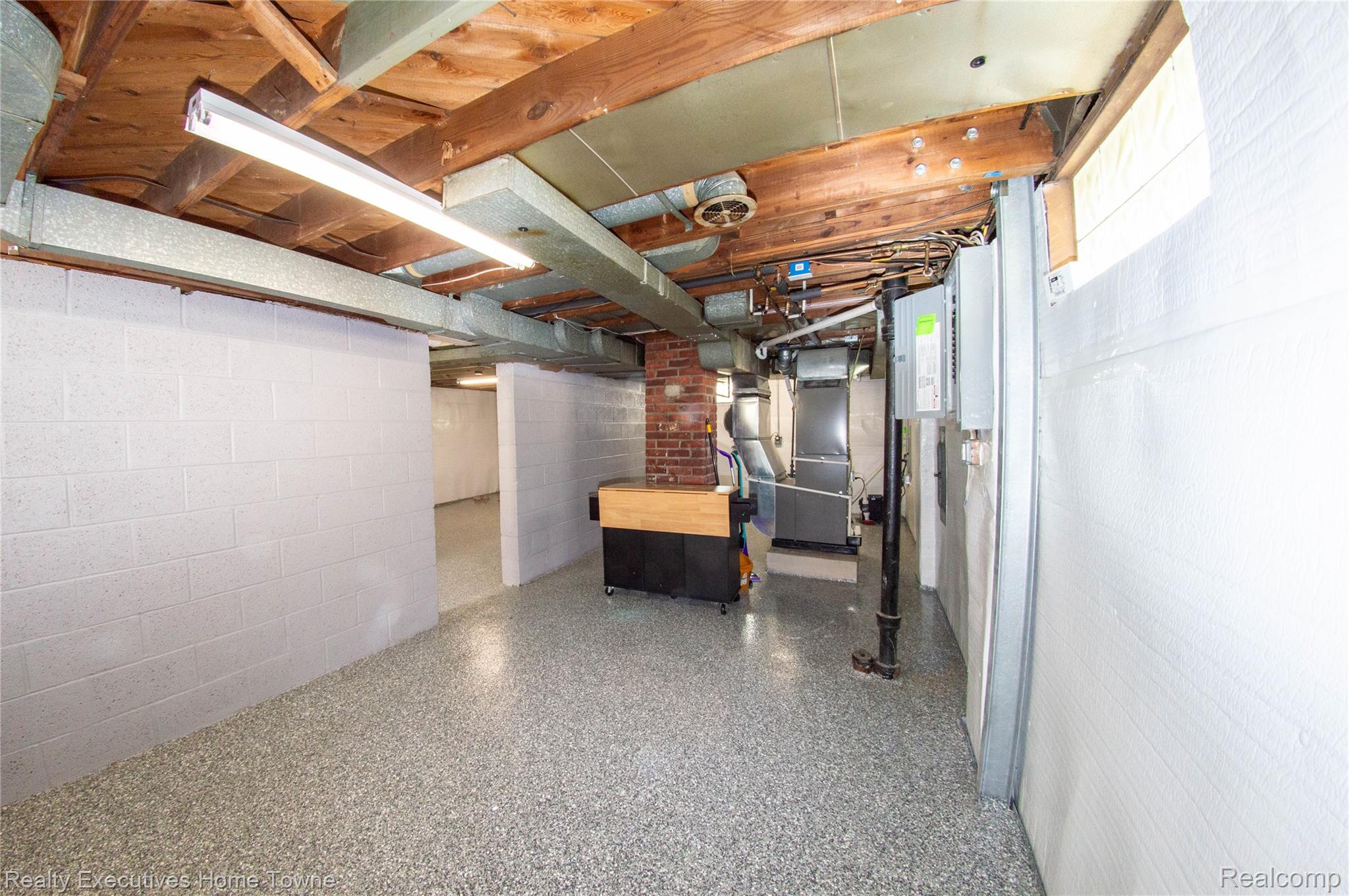 2676 Cumberland Road Berkley, MI 48072 - Photo 32 of 38 Spacious basement area featuring a gray speckled flooring, white painted block walls, exposed wood ceiling joists, and fluorescent lighting