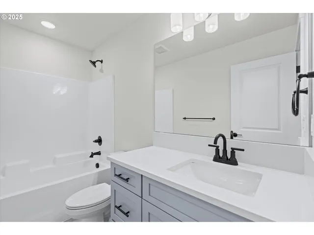 a bathroom with a sink a toilet a mirror a vanity and bathtub