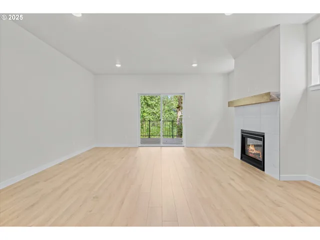 a view of empty room with wooden floor and fireplace