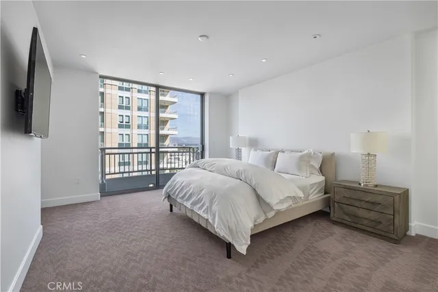 a spacious bedroom with a bed and a flat tv screen on dresser