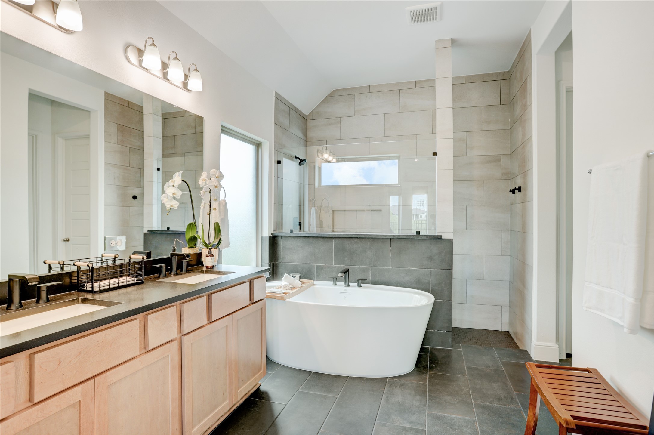 619 Rita Blanca Drive Webster, TX 77598 - Photo 17 of 44 The modern primary bathroom with features a freestanding tub, dual sinks with ample counter space, and elegant tile work. Natural light streams in through a large window, enhancing the room's bright, airy feel.