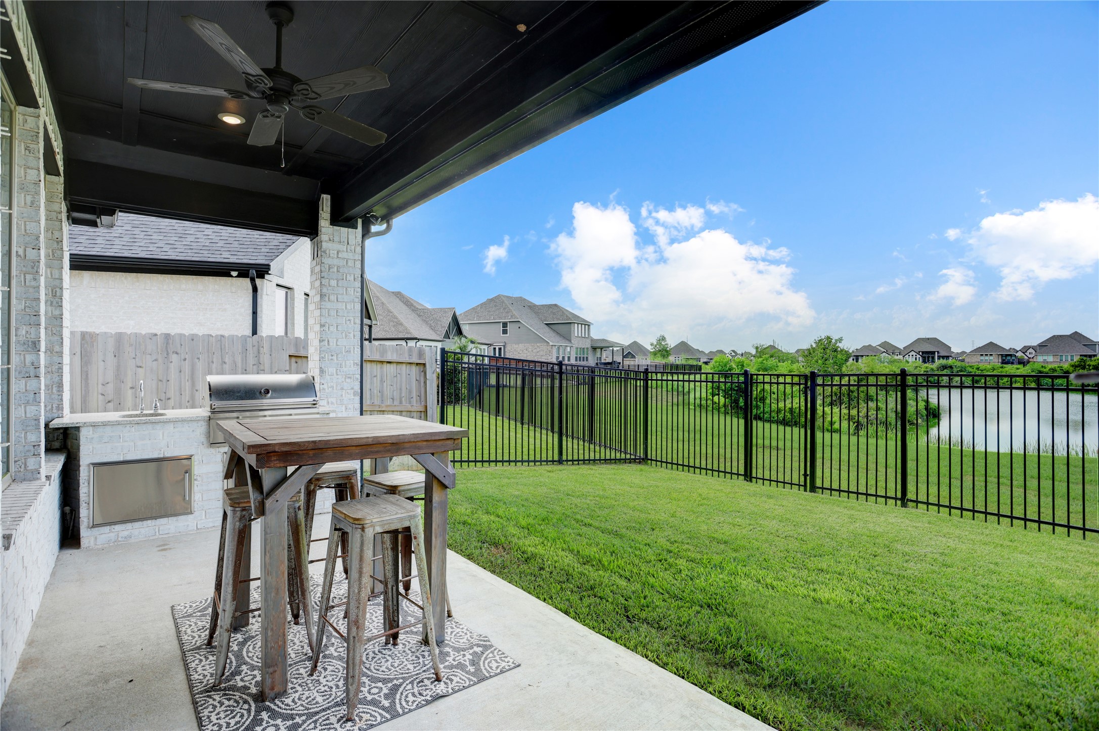 619 Rita Blanca Drive Webster, TX 77598 - Photo 29 of 44 Enjoy the back yard complete with covered patio with a ceiling fan, summer kitchen, water views unencumbered by the black rod iron fence, providing a serene and private outdoor space.