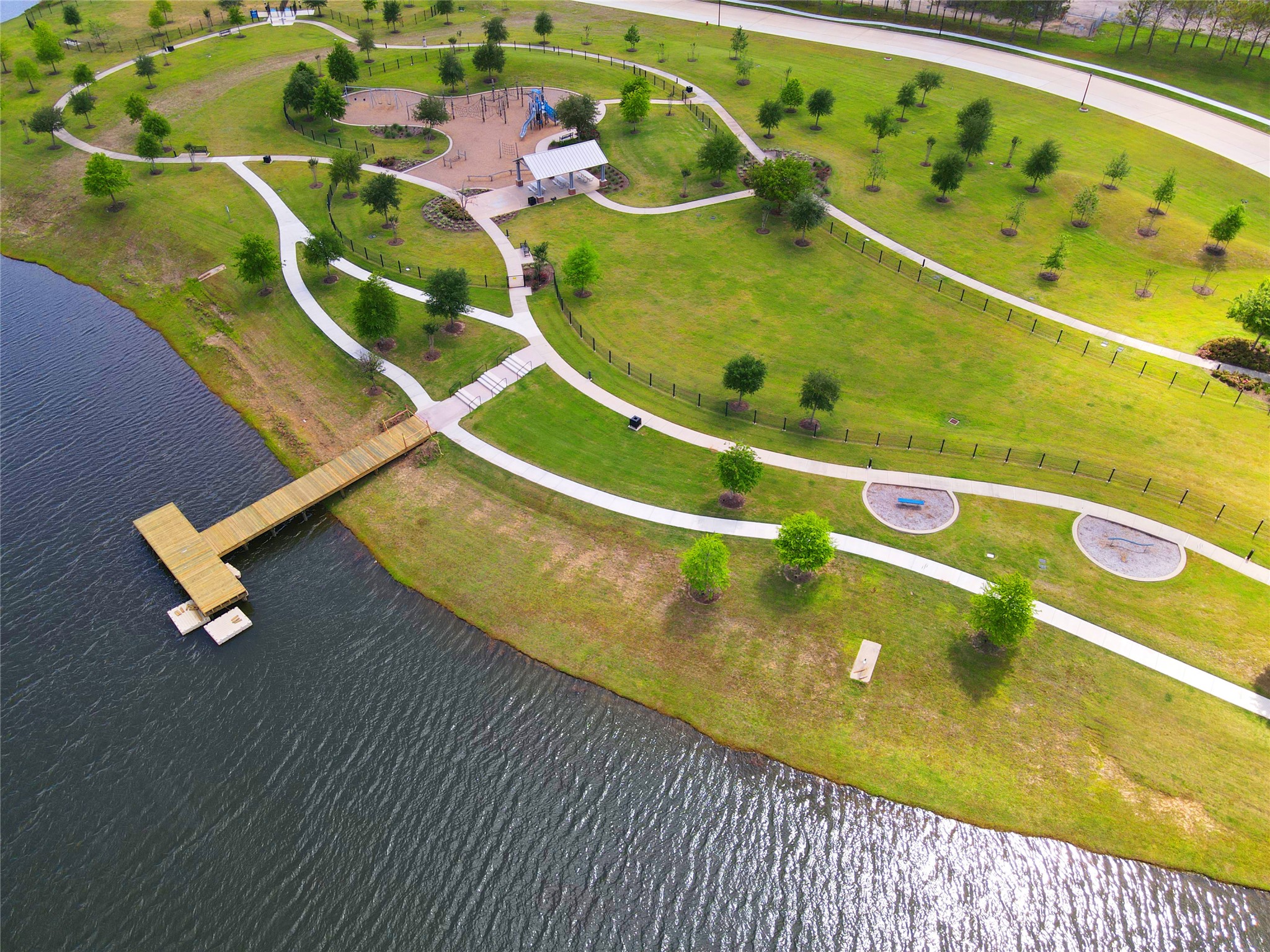 619 Rita Blanca Drive Webster, TX 77598 - Photo 40 of 44 Edgewater's scenic park with lush green spaces, winding pathways, a playground, and a picnic area. It features a waterfront view with a wooden pier extending into the water, ideal for outdoor activities and relaxation.