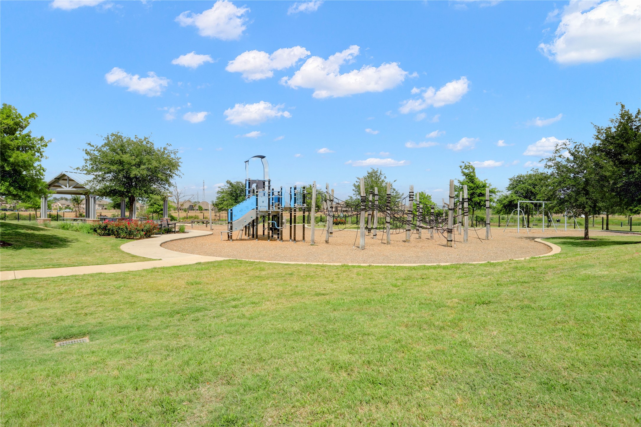 619 Rita Blanca Drive Webster, TX 77598 - Photo 42 of 44 A spacious playground set in a well-maintained park with lush green grass, a modern play structure, and a shaded pavilion, perfect for small gatherings.