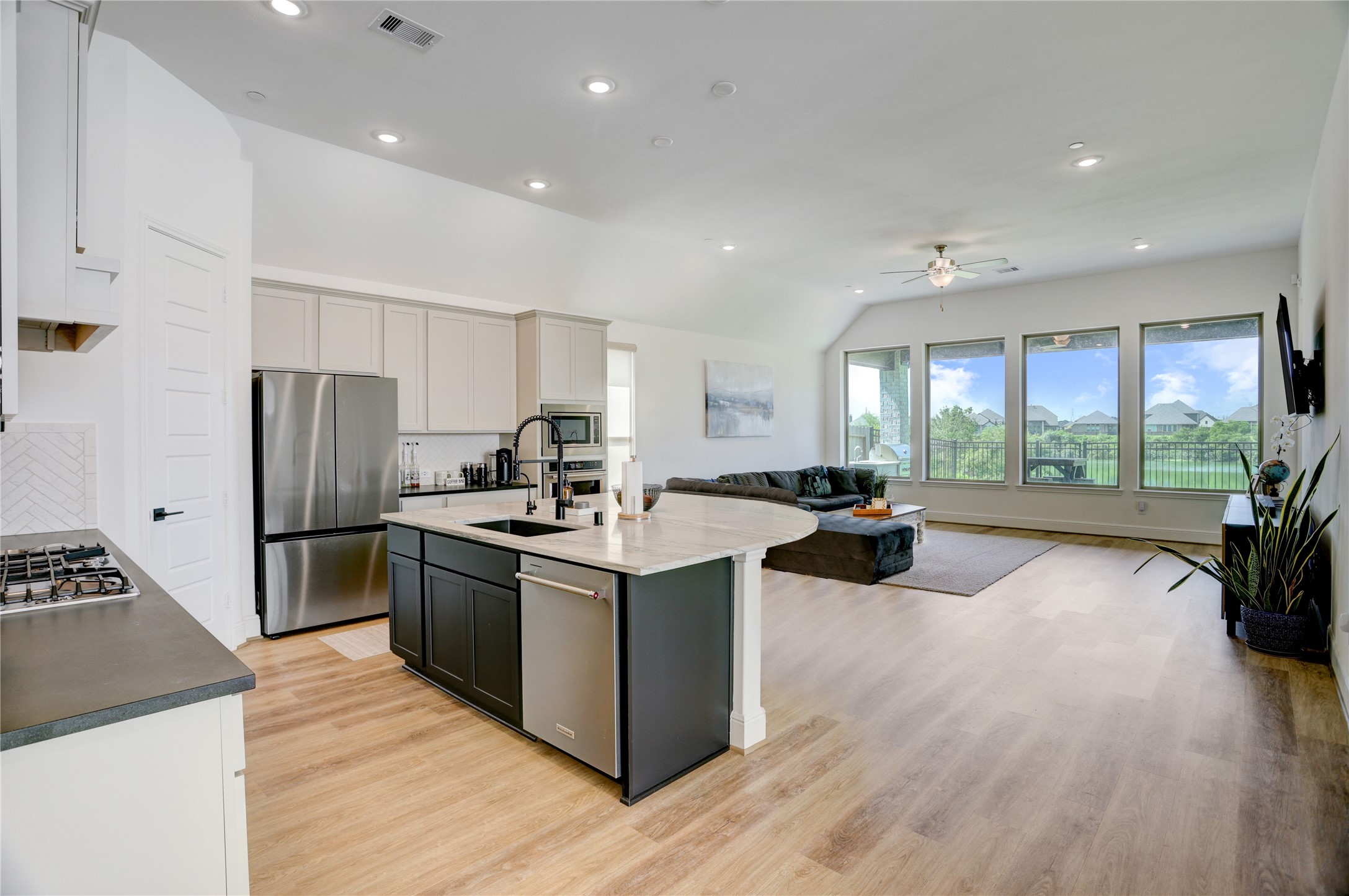 619 Rita Blanca Drive Webster, TX 77598 - Photo 5 of 44 This spacious open-concept living area features a modern kitchen with stainless steel appliances, an island, and light plank flooring.