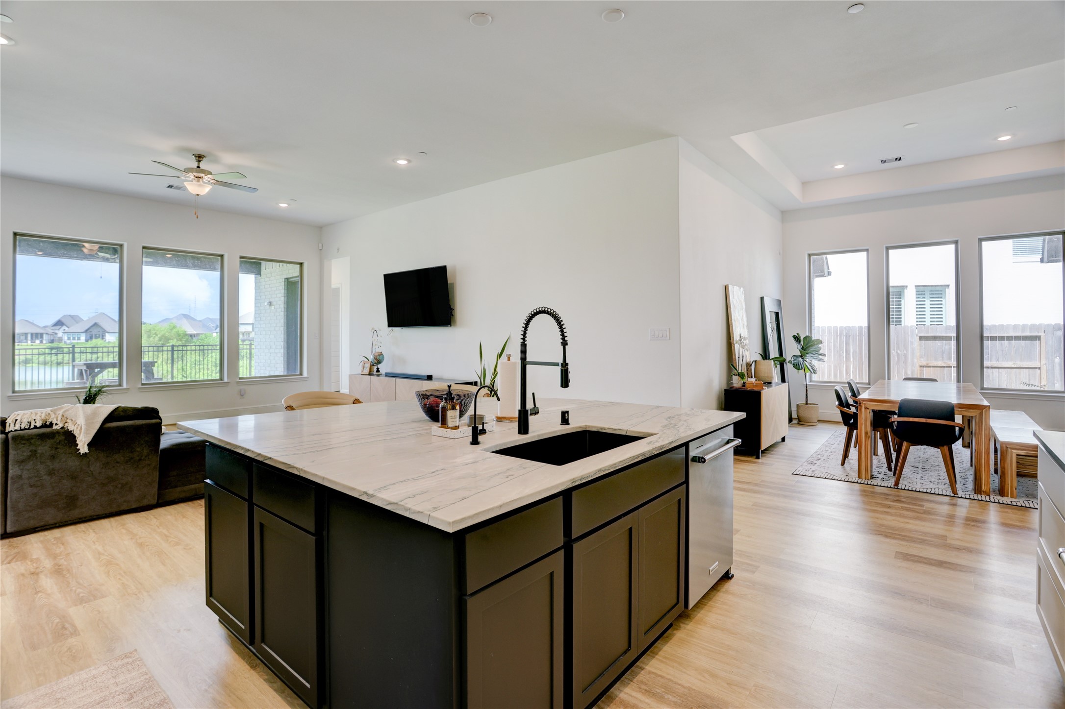 619 Rita Blanca Drive Webster, TX 77598 - Photo 43 of 44 The floor plan showcases a spacious, open-concept living area with a modern kitchen island, bright natural lighting, and large windows offering a scenic view. The dining area is adjacent, featuring a wooden table and additional windows for a bright and airy feel.