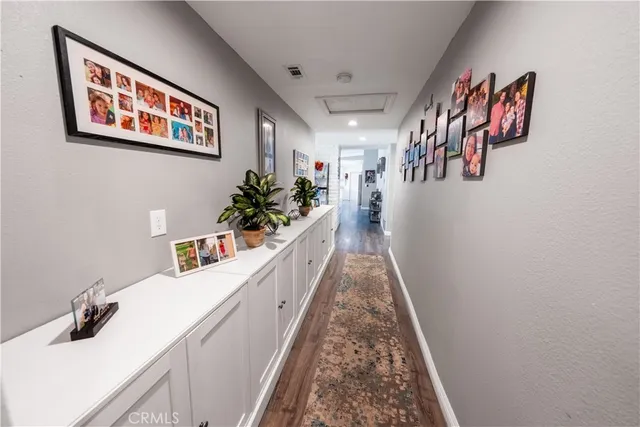 a hallway with painting on the wall and a potted plant