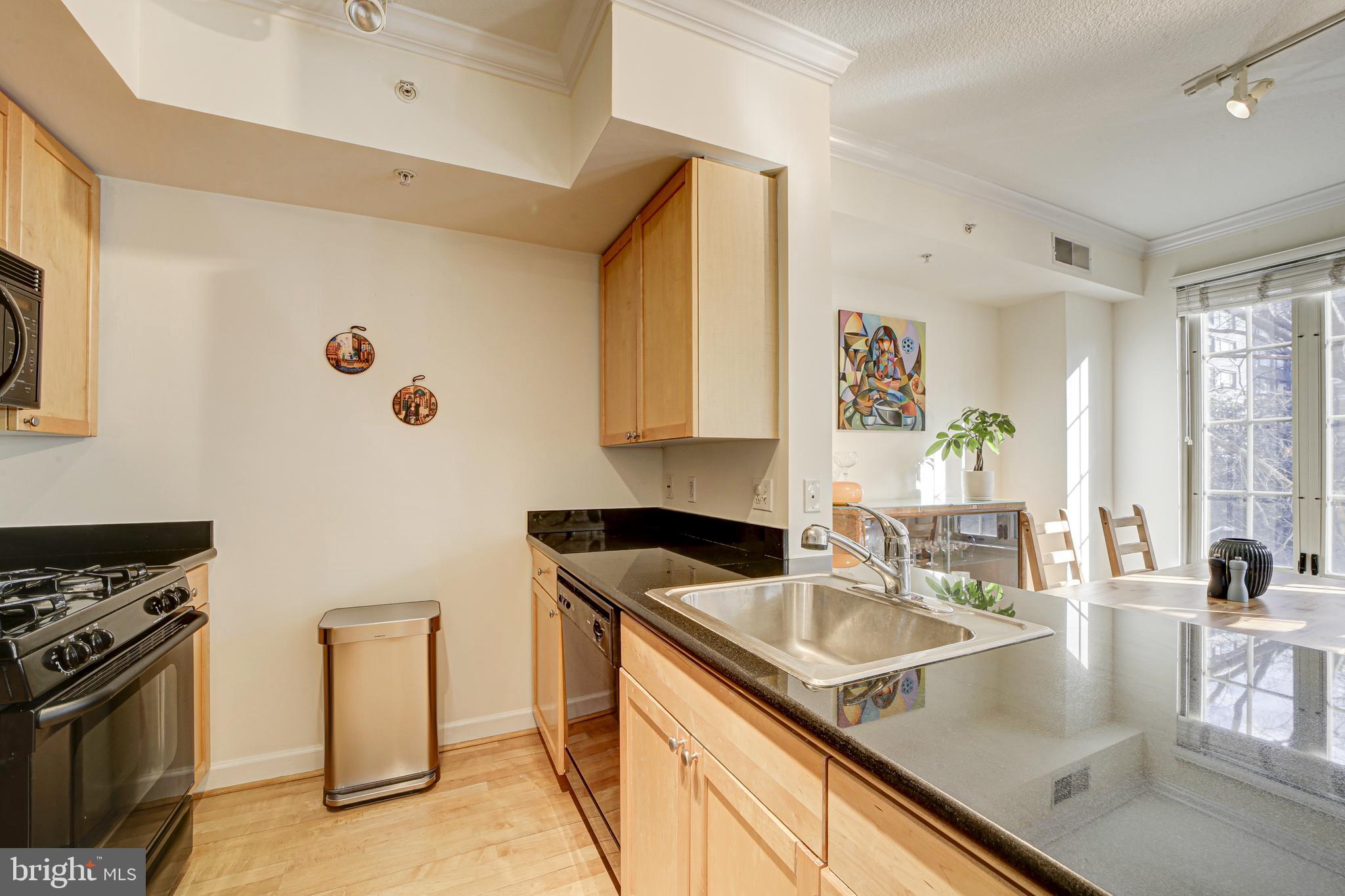 1441 Rhode Island Avenue Northwest, Unit 419 Washington, DC 20005 - Photo 7 of 25 a kitchen with granite countertop a sink a stove and wooden cabinets