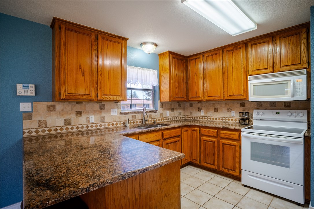 1016 Clark Street Mexia, TX 76667 - Photo 11 of 36 a kitchen with granite countertop cabinets stainless steel appliances a sink and window