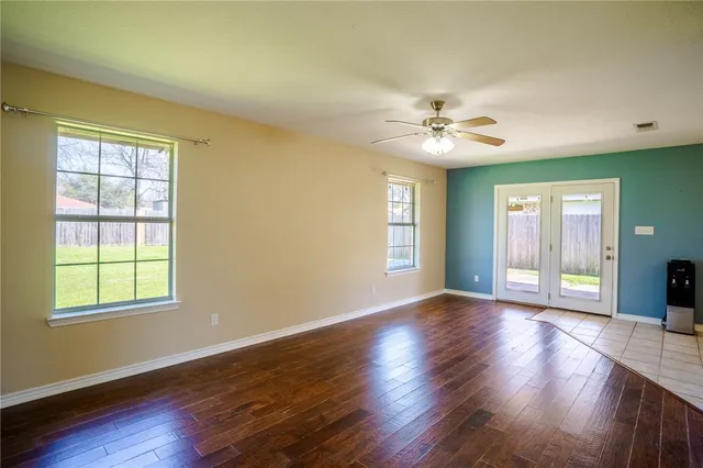 a view of an empty room with window and wooden floor