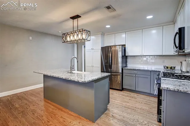 a kitchen with kitchen island granite countertop stainless steel appliances a sink stove and refrigerator