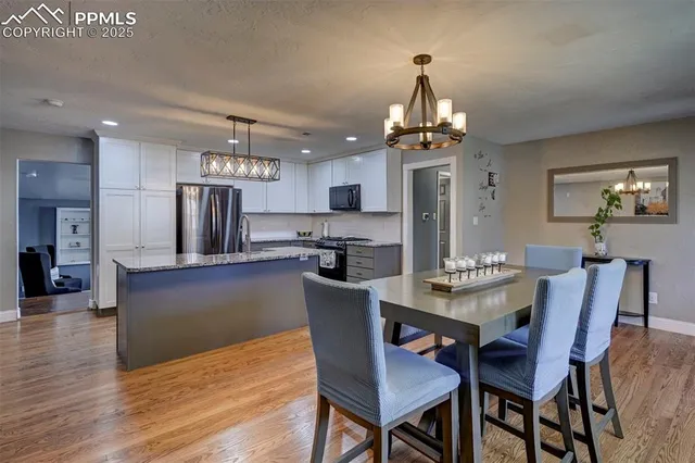 a dining room with wooden floor a chandelier a wooden table and chairs