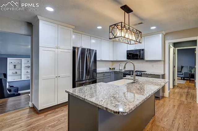 a kitchen with stainless steel appliances granite countertop a sink refrigerator and cabinets